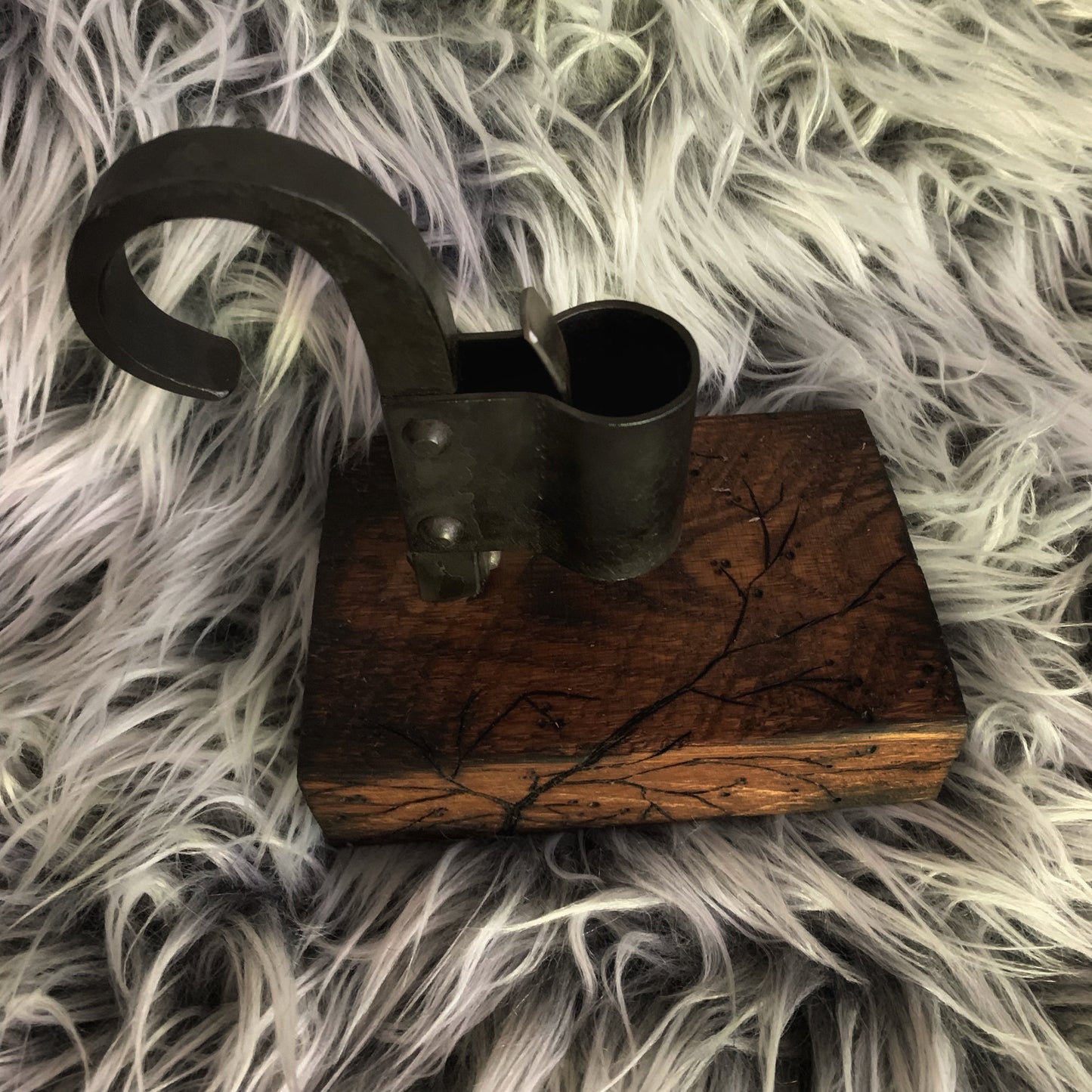 Decorative metal candle holder on a wooden block with a natural wood finish, placed on a textured gray surface.