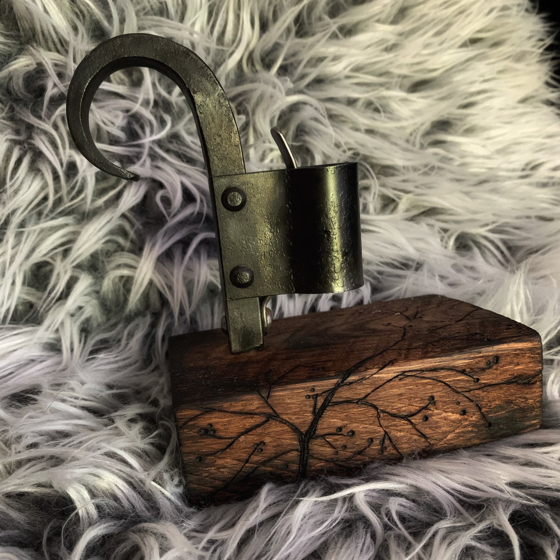 Decorative item with a wooden base and metal hook on a fluffy gray surface