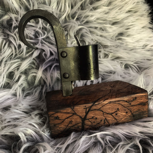 Decorative item with a wooden base and metal hook on a fluffy gray surface